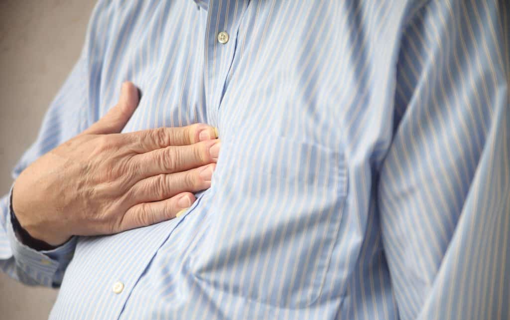 Hand placed on center of man's chest due to heartburn pain