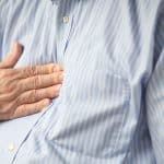 Hand placed on center of man's chest due to heartburn pain