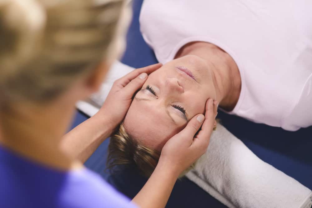 Reiki Master performing reiki therapy to woman