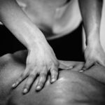 Black and white image of a pair of hands massaging a person's back