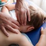 Massage being performed by a massage therapist to the back of a little boy’s neck.