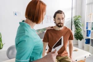 massage therapist rests hand on client's shoulder to soothe client