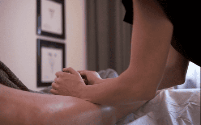 Massage therapist using the forearms to massage client's leg