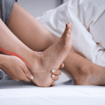 woman holding back of ankle due to achilles tendinitis pain