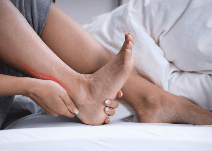 woman holding back of ankle due to achilles tendinitis pain